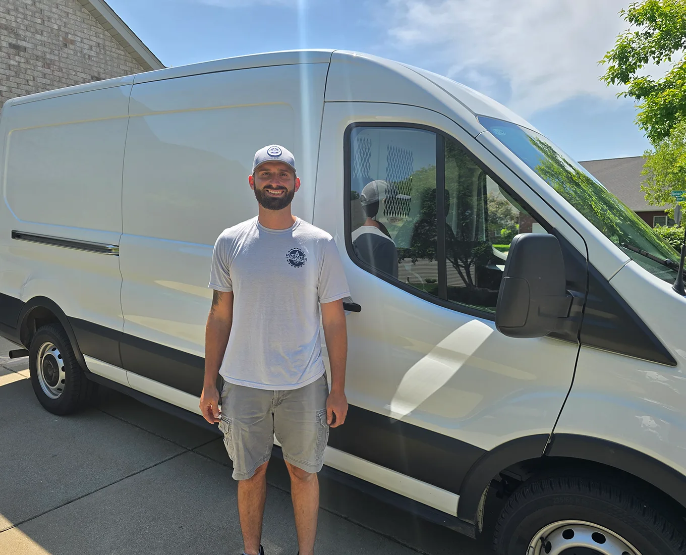 owner of premier heating & air standing outside in front of a company service van.