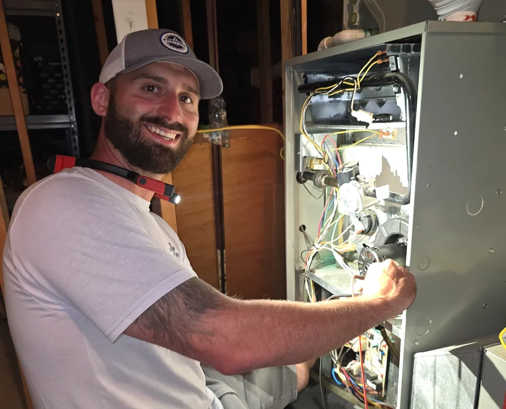 Premier Heating & Air HVAC Technician working on furnace unit in basement in springfield il